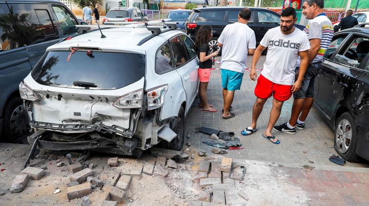 Bewohner der Stadt Sderot stehen neben einem durch Geschosse beschädigten Auto.