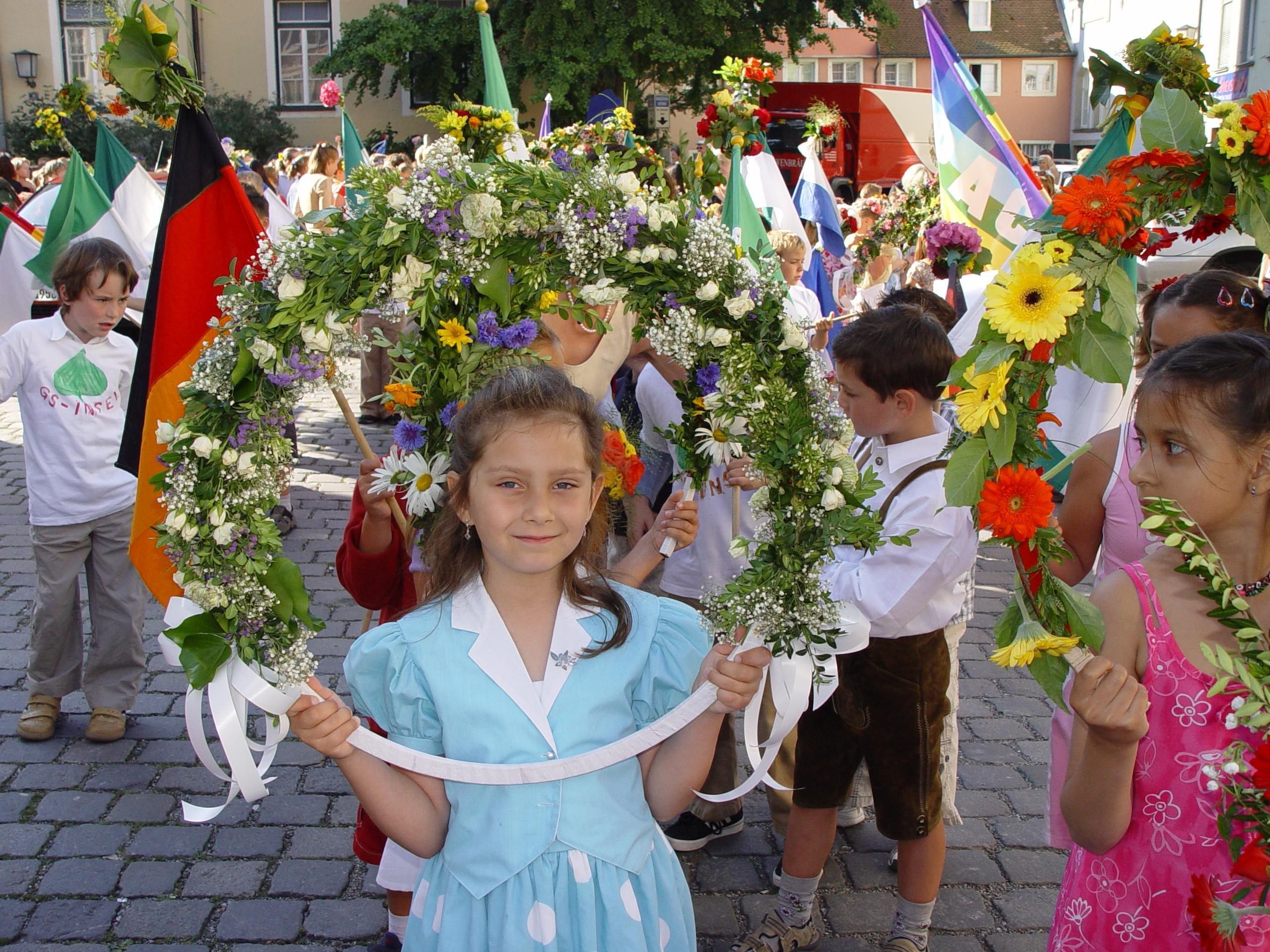 Beim Lindauer Kinderfest laufen die Mädchen beim Umzug mit großen Blumenkränzen, die Buben mit Fahnen.