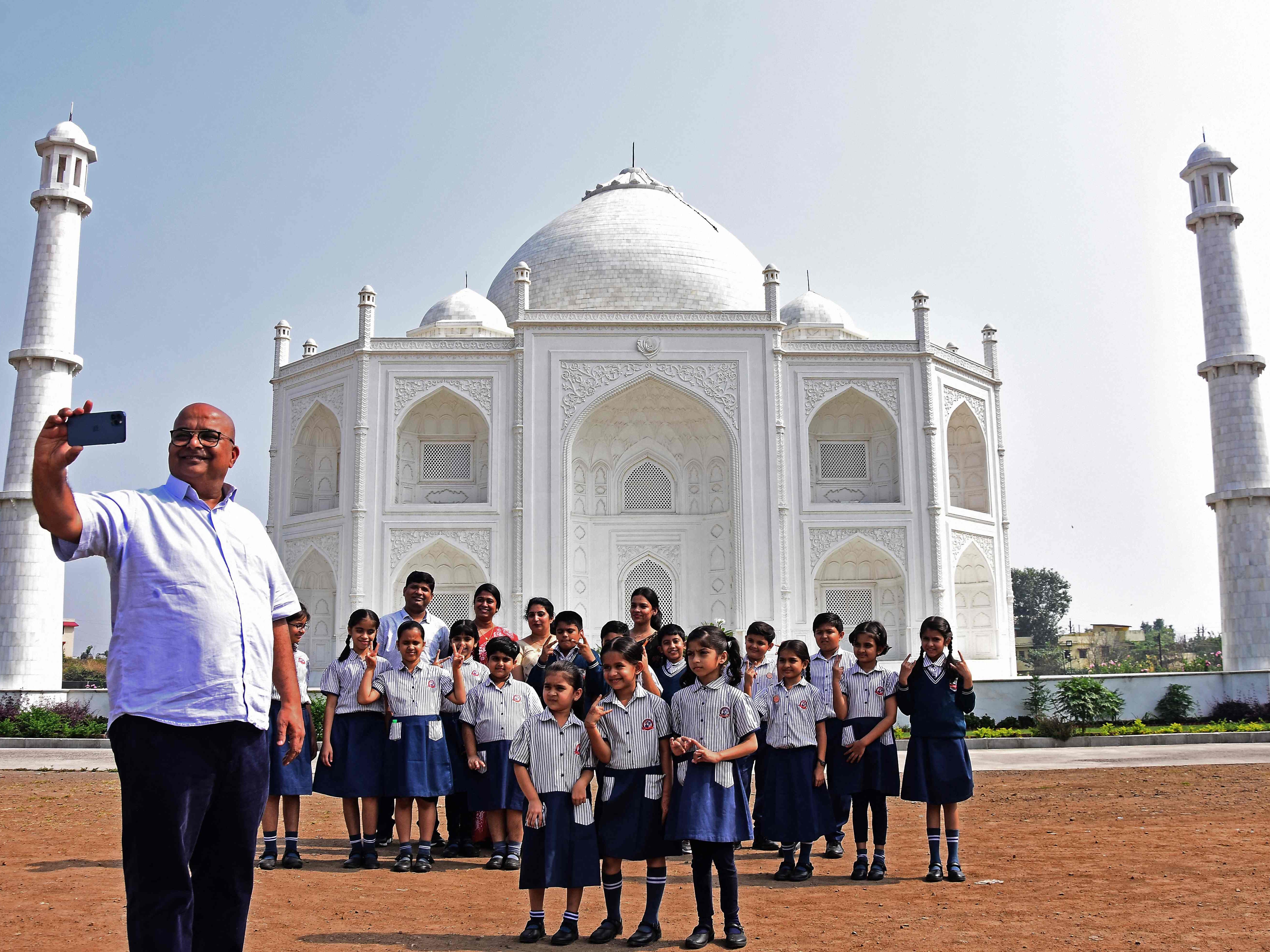 Anand Prakash Chouksey posiert mit Schulkindern vor dem Nachbau des Taj Mahal.