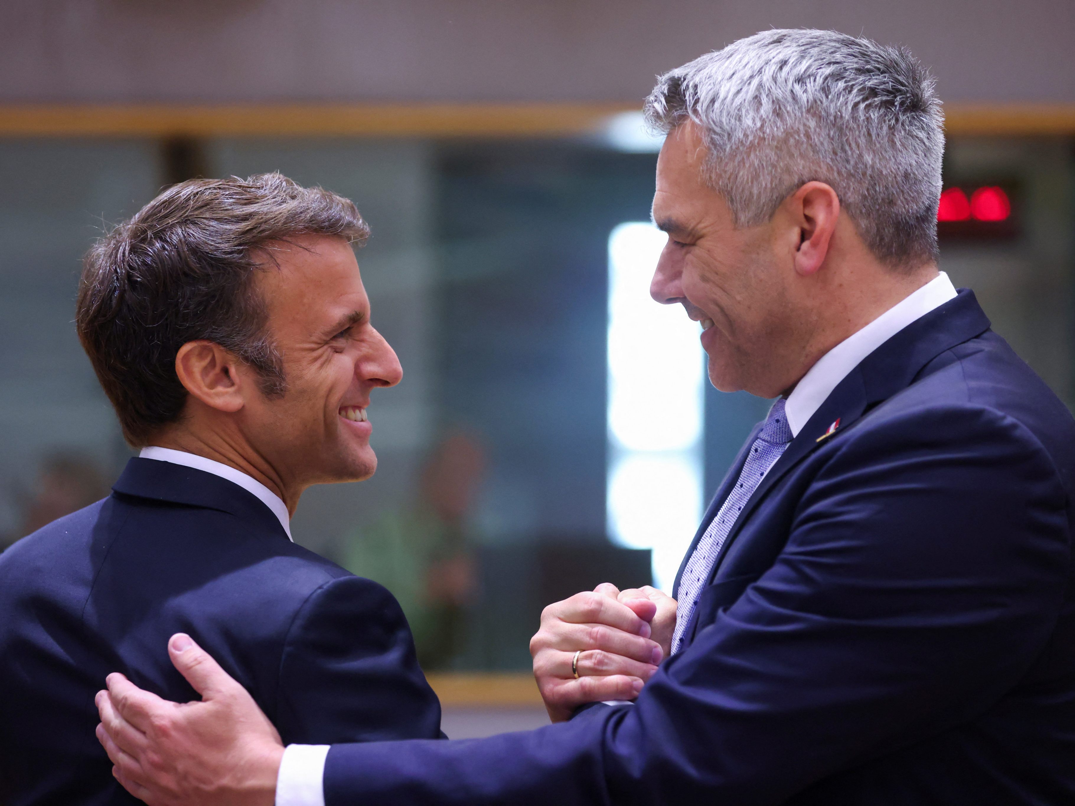 Kanzler Nehammer und Frankreichs Präsident Macron mit kumpelhaftem Handschlag beim EU-Gipfel in Brüssel.