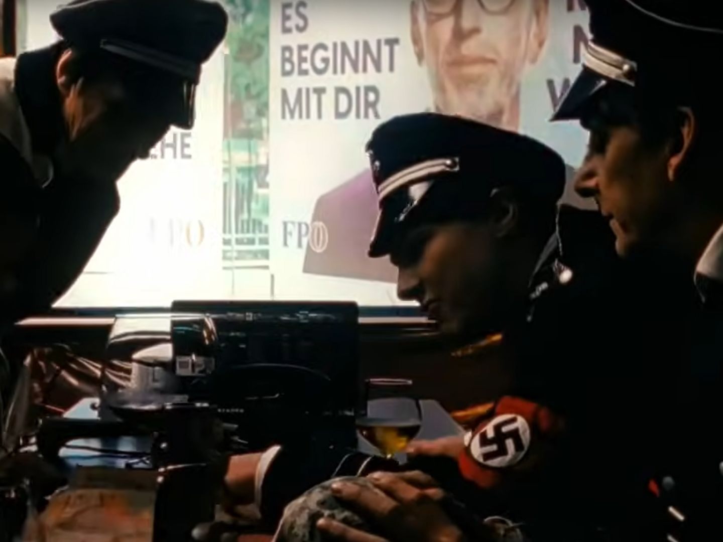 Die Performer sind in Uniformen mit Hakenkreuz-Binden und Hitler-Bart zu sehen.