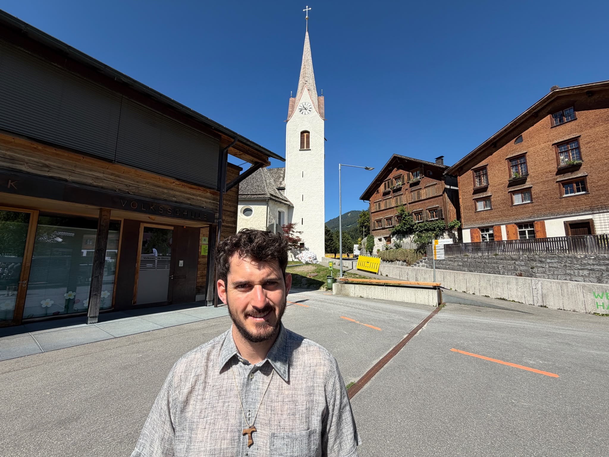 Kaplan Gabriel Steiner steht vor einer seiner künftigen Wirkungsstätten, der Pfarrkirche in Blons.